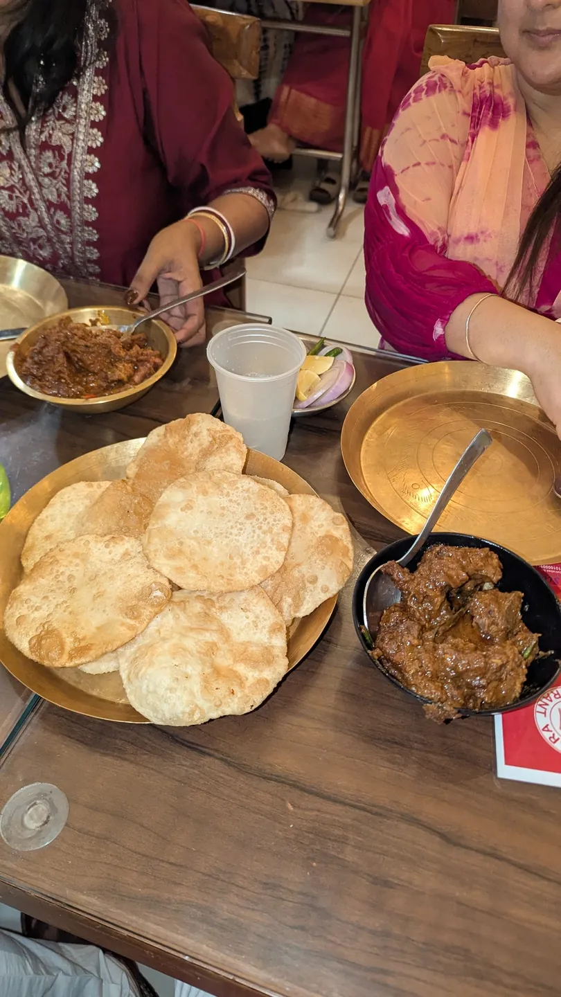 Diners sharing a Bengali meal served on brass plates
