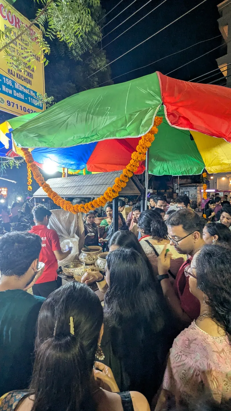 A lively evening market beneath bright umbrellas and marigold garlands