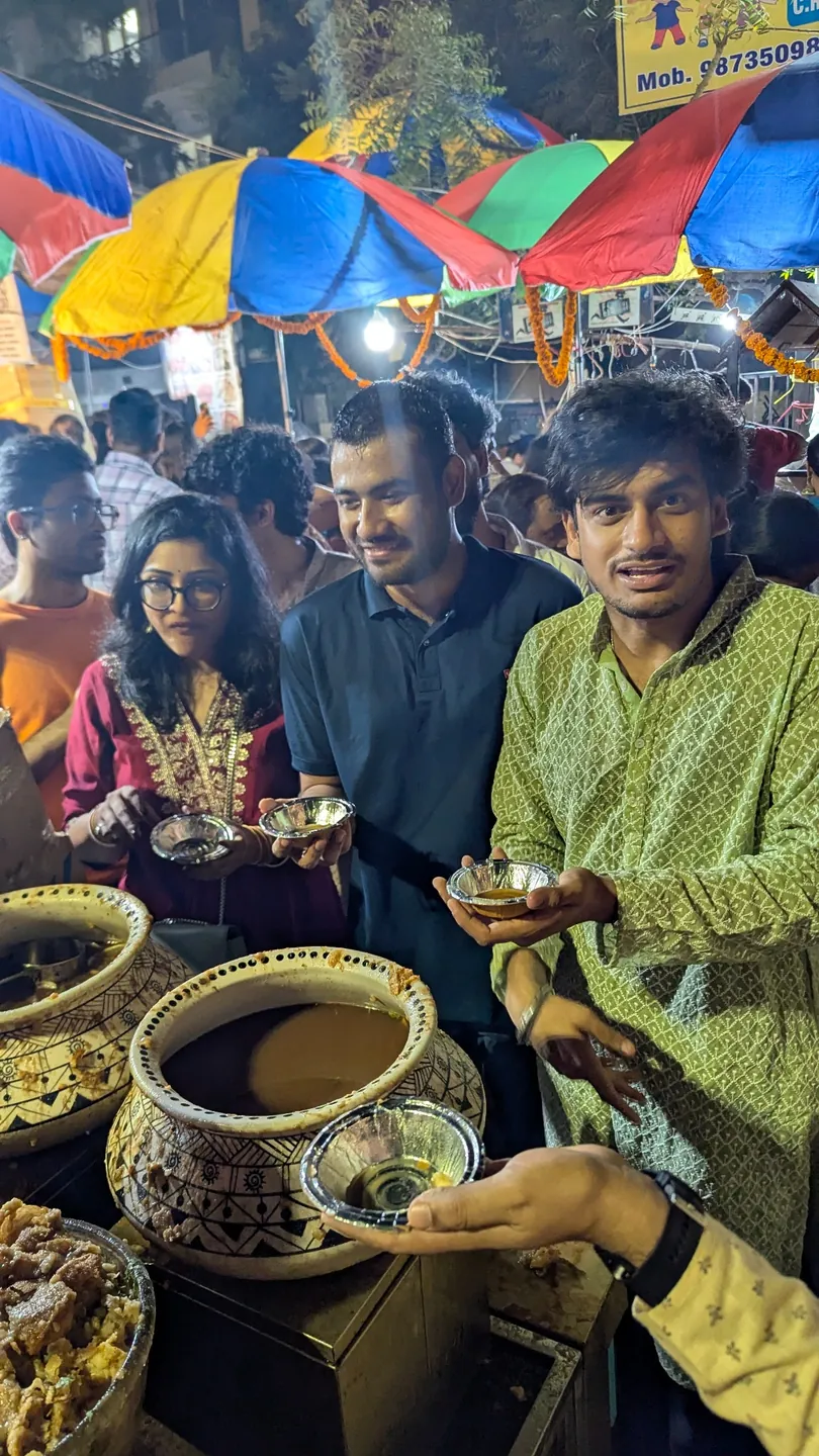 Friends gathered around a food stall under colourful market umbrellas