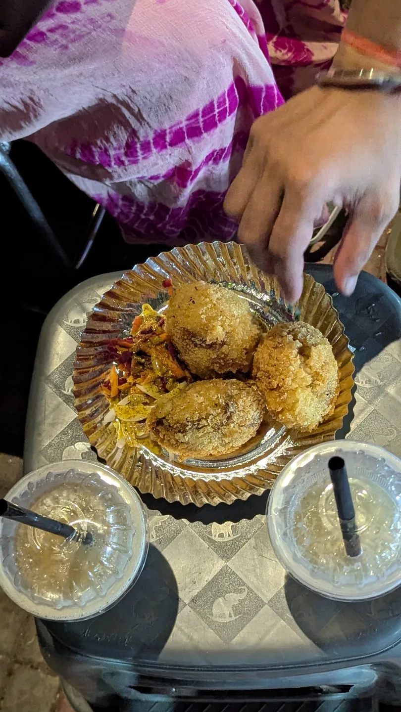 Friends sharing plates of street-food snacks and small cups around a table
